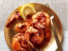 grilled shrimp on a gold plate with lemon wedges and a fork next to it