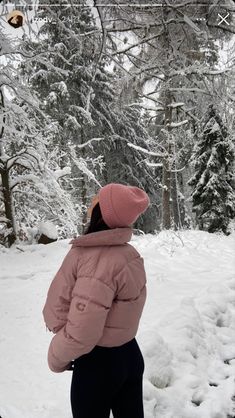 a person standing in the snow wearing skis and a pink jacket with a hood on