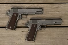 two handguns sitting side by side on top of a wooden table next to each other