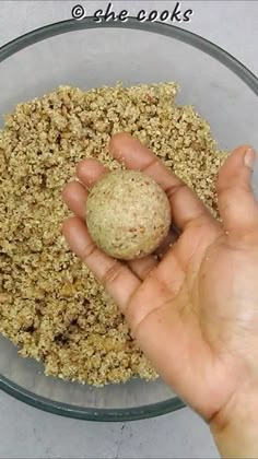 a hand holding a ball in a bowl filled with oatmeal flakes