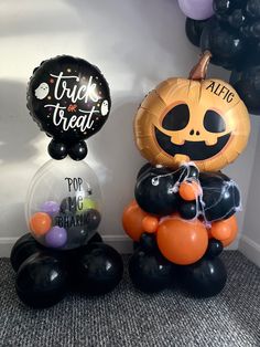 two halloween balloons sitting on the floor next to each other, one with a jack - o'- lantern balloon