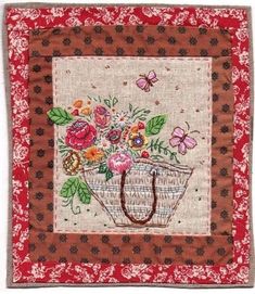 a red and white wall hanging with flowers in a basket on the front, and butterflies flying over it