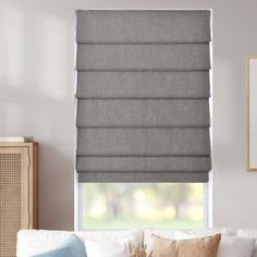 a living room with a white couch and window covered in grey roman blind shades on the windowsill