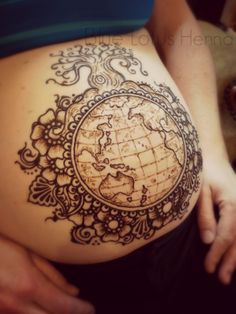 a pregnant woman's belly with a world map tattoo on the side of her stomach