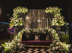 a couch with flowers and greenery on it in front of a decorated stage at night