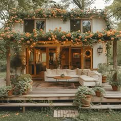 a couch sitting on top of a wooden deck next to a white house covered in flowers