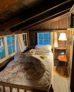 a bed sitting in the corner of a room under a roof next to two windows