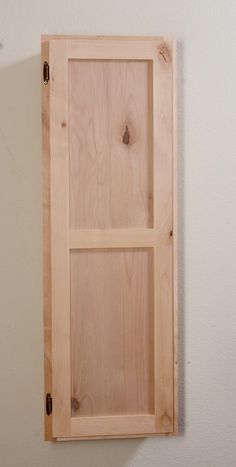 an unfinished wooden cabinet hanging on the wall