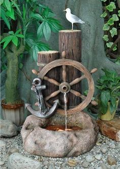 a bird sitting on top of a wooden spinning wheel with an anchor and seagull