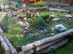 an outdoor garden with logs, rocks and flowers in the grass next to a building