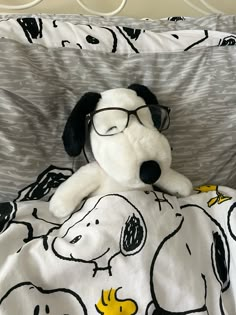 a stuffed dog wearing glasses laying on top of a bed covered in a white and black blanket