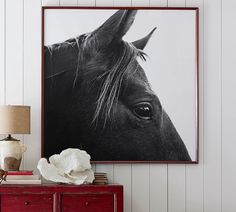 a black and white horse is on the wall next to a red cabinet with a lamp