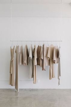 there are many shirts hanging on the clothes rack in front of white walls and flooring