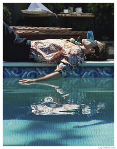 a man laying on the edge of a swimming pool