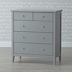 a grey chest of drawers in front of a wall