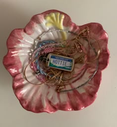 a pink flower shaped plate with charms and a badge on the front that says hottie