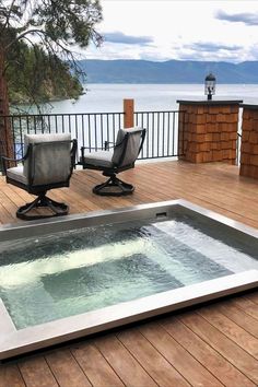 an outdoor hot tub on a deck with two chairs and a table overlooking the water