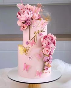 a three tiered cake with pink flowers and butterflies on it