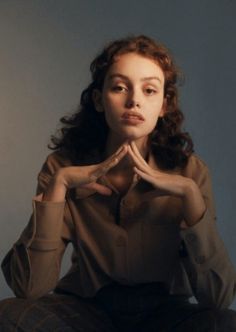 a woman sitting on the floor with her hands together