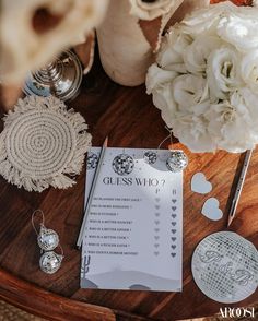 a wooden table topped with white flowers and cards