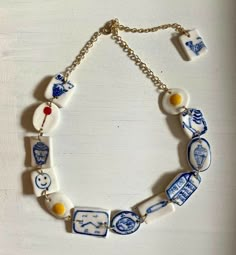 a blue and white bracelet with various items on the link, hanging from a gold chain