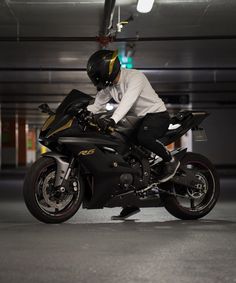 a man sitting on top of a black motorcycle in a parking garage next to a green light