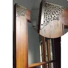 an intricately carved wooden mirror frame hangs from the ceiling in front of a window