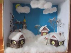 a box that has some houses in it with snow on the ground and clouds above