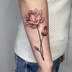 a woman's arm with a pink flower tattoo on the left side of her arm