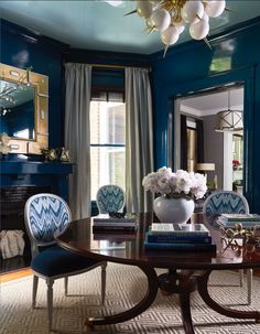 a dining room with blue walls and chairs in it, along with a chandelier hanging from the ceiling