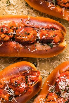 three hot dogs covered in sauce and shredded parmesan cheese