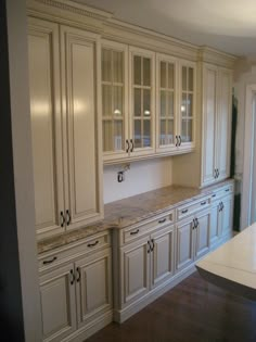 an empty kitchen with white cabinets and marble counter tops in the middle of the room