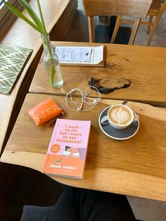 there is a cup of coffee and a book on the table next to some glasses