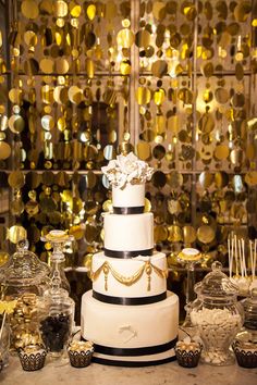 a white and black wedding cake surrounded by gold confetti