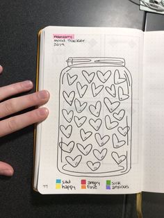 a hand holding an open notebook with hearts drawn on it