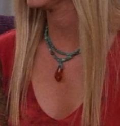 a woman with long blonde hair wearing a red shirt and necklace on her neck is looking to the side