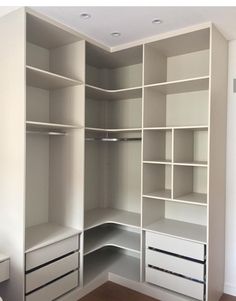 an empty closet with white shelves and drawers