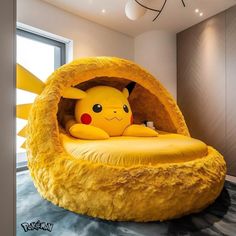 a large stuffed pikachu is sitting in a bed shaped like a pokemon pillow