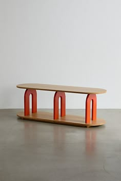 a wooden table with two red arches on the top and bottom, in front of a white wall