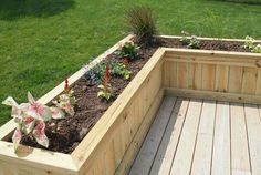 a wooden planter filled with lots of flowers on top of a grass covered field