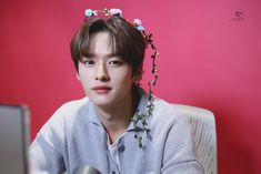 a young man sitting in front of a computer screen wearing a flower crown on his head