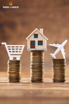 small model house sitting on top of stacks of coins with an airplane flying over them