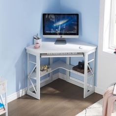 a corner desk with a computer monitor and keyboard on it in a blue walled room