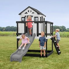 three children playing on a play set in the grass