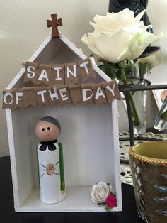 a small wooden dollhouse with a saint of the day decoration