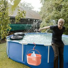 a man standing next to a large blue swimming pool with water pouring out of it