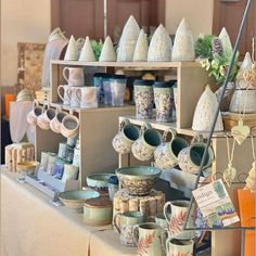 an assortment of pottery is on display at the table with many cups and saucers