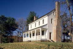 a large white house sitting on top of a lush green hillside next to trees and grass