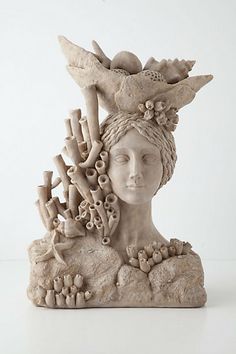 a sculpture of a woman's head with corals and shells in her hair