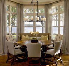 a dinning room table with chairs around it in front of two large windows that look out onto the water